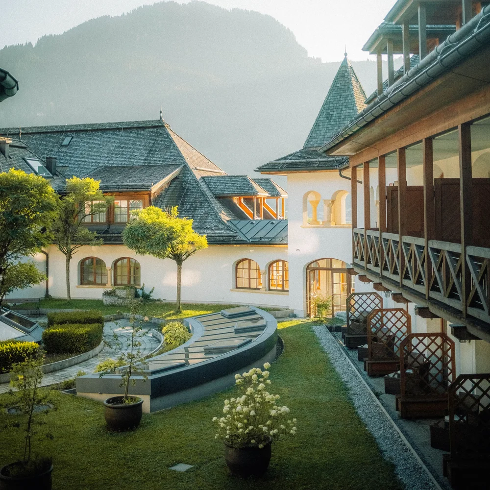 So schön: Kitzbühel-Urlaub mit Kindern Historisches Gebäude mit Garten und Bergen im Hintergrund bei Sonnenlicht