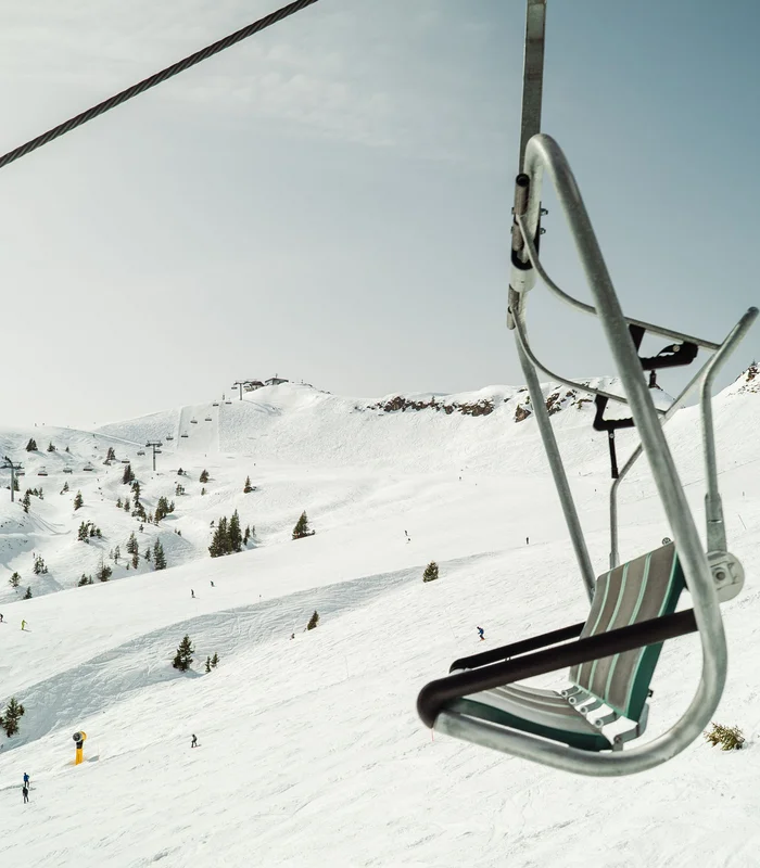 Ultimatives Skihotel in Kitzbühel Leerer Skilift auf verschneitem Berg mit Skifahrern im Hintergrund
