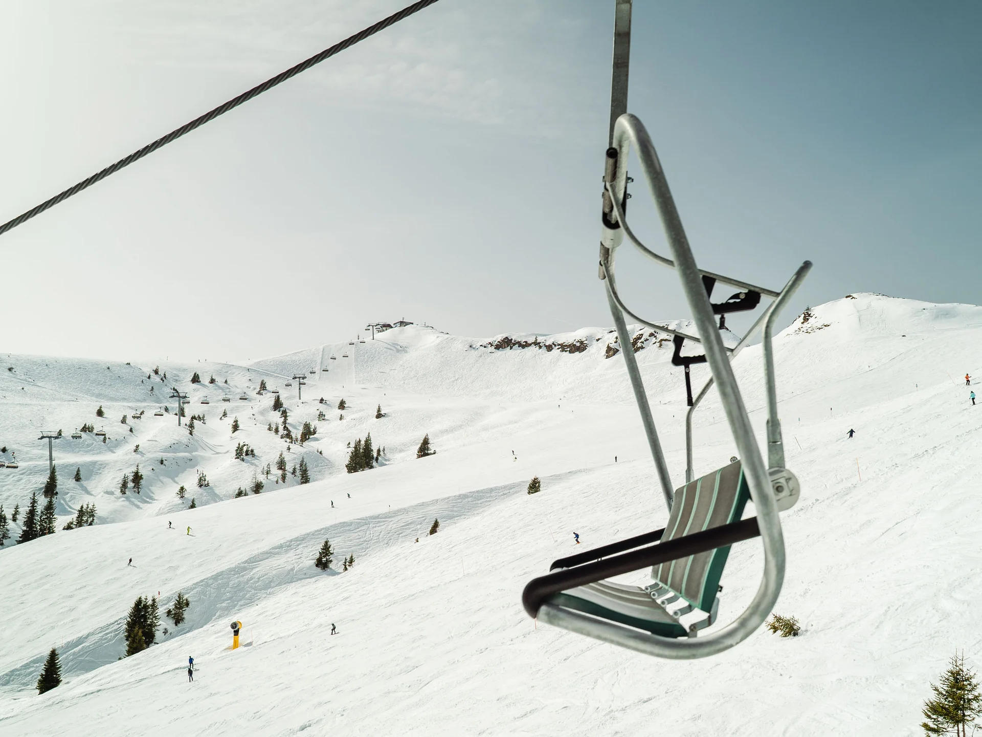 Bilder, die Sie sehen müssen. Leerer Skilift auf verschneitem Berg mit Skifahrern im Hintergrund