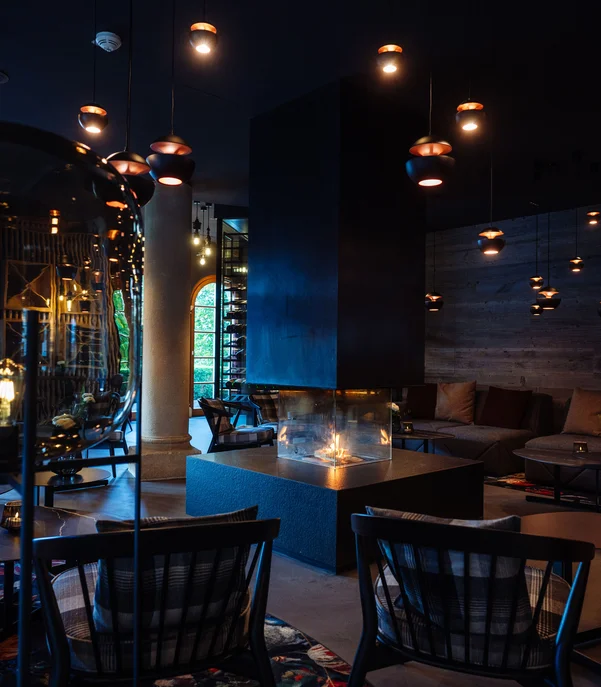 Hotel mit Klavier und Livemusik | Die Bar im Schlosshotel Kitzbühel Gemütlicher Lounge-Bereich mit Kamin und moderner Beleuchtung