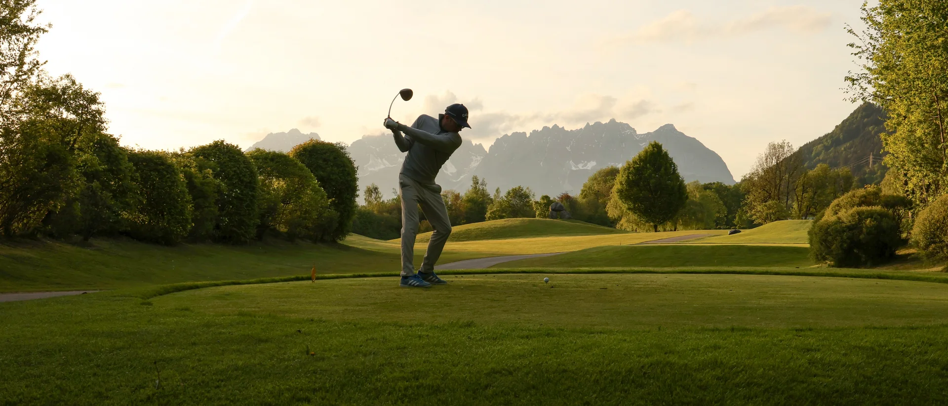 Das Golfhotel in Kitzbühel Abendliche Golfrunde mit einer Silhouette von einem Golfspieler mit Blick auf den Wildenkaiser