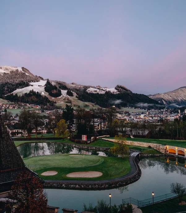 Silvester in Kitzbühel = Hotel, Party, Champagner Blick auf Golfplatz mit Bergen und Dorf im Hintergrund bei Sonnenaufgang