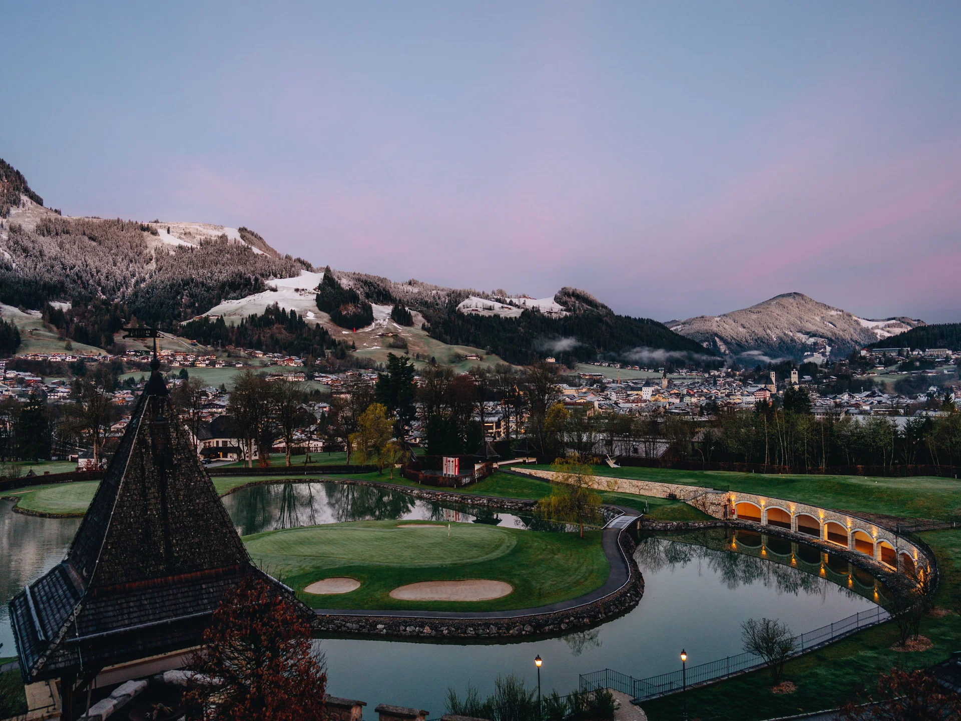 Bilder, die Sie sehen müssen. Blick auf Golfplatz mit Bergen und Dorf im Hintergrund bei Sonnenaufgang