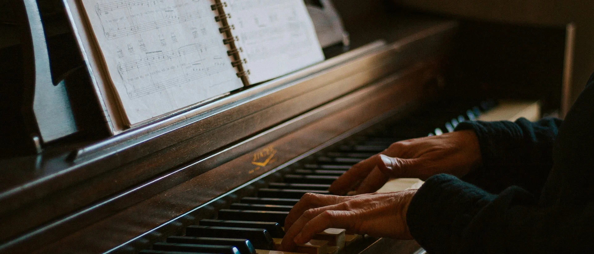 Kulturhotel. Schlosshotel. Kitzbühel. Person spielt Klavier mit Notenblatt auf einem Holzklavier