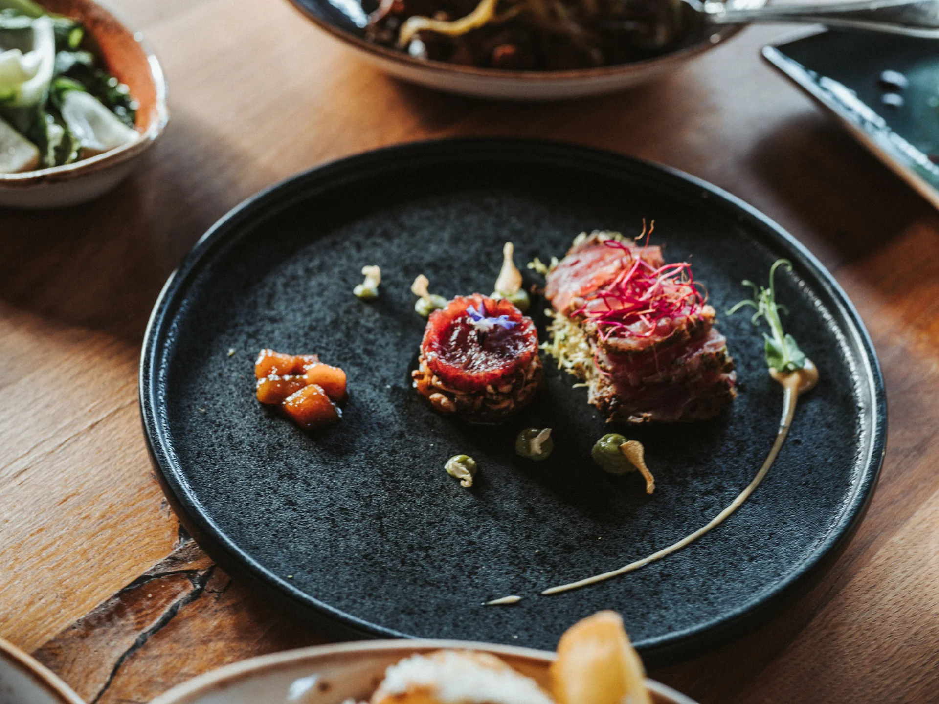 Bilder, die Sie sehen müssen. Fein angerichtete Gourmetvorspeise auf schwarzem Teller mit Gemüse und Soße