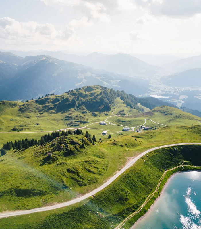 Ausflugsziele & Sehenswürdigkeiten rund um Kitzbühel Grüne Hügel mit Straßen und kleineren Gebäuden neben einem See im Bergland