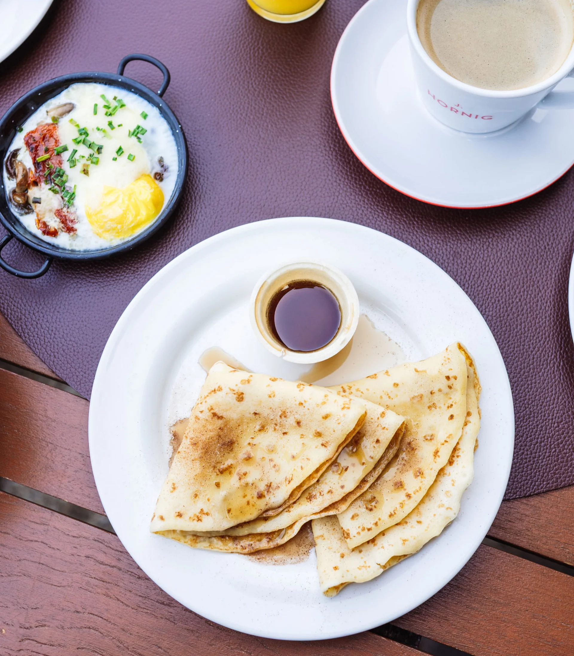 Sie haben Lust auf ein köstliches Essen? Frühstück mit Pfannkuchen, Ei, Brötchen, Kaffee und Müsli mit Früchten