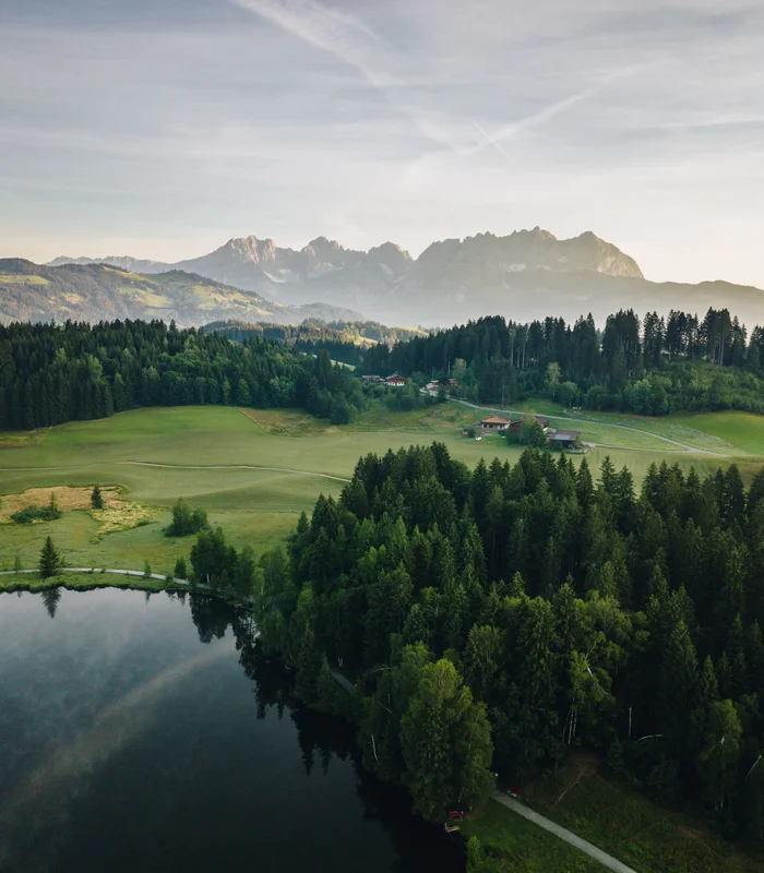 Ausflugsziele & Sehenswürdigkeiten rund um Kitzbühel Landschaft mit See, Wald und Bergen im Hintergrund bei bewölktem Himmel