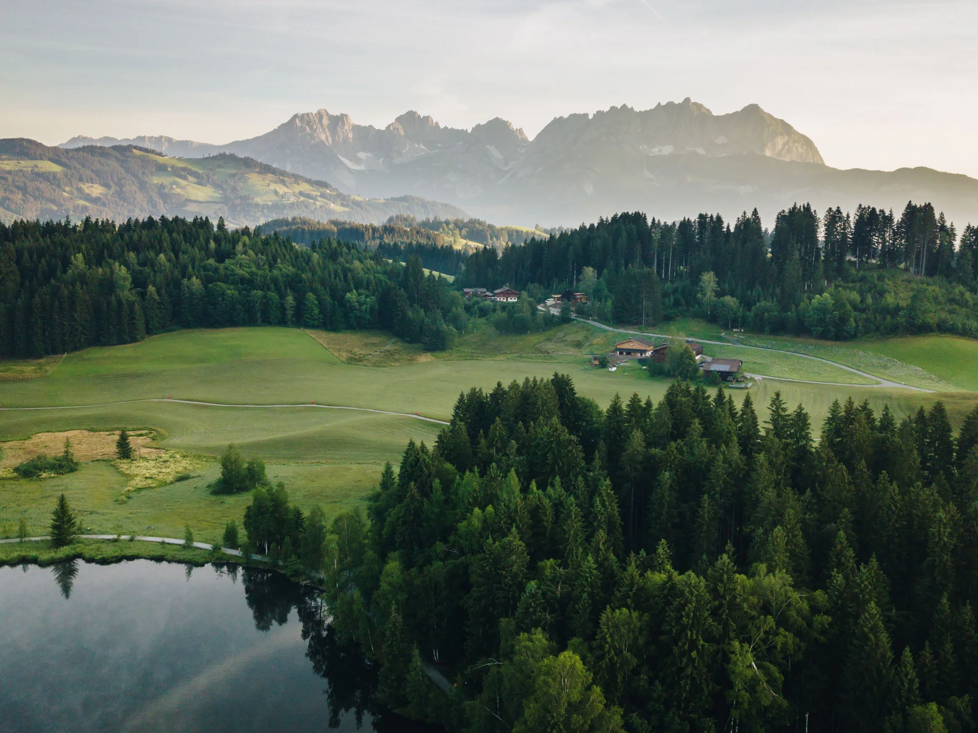 Bilder, die Sie sehen müssen. Landschaft mit See, Wald und Bergen im Hintergrund bei bewölktem Himmel