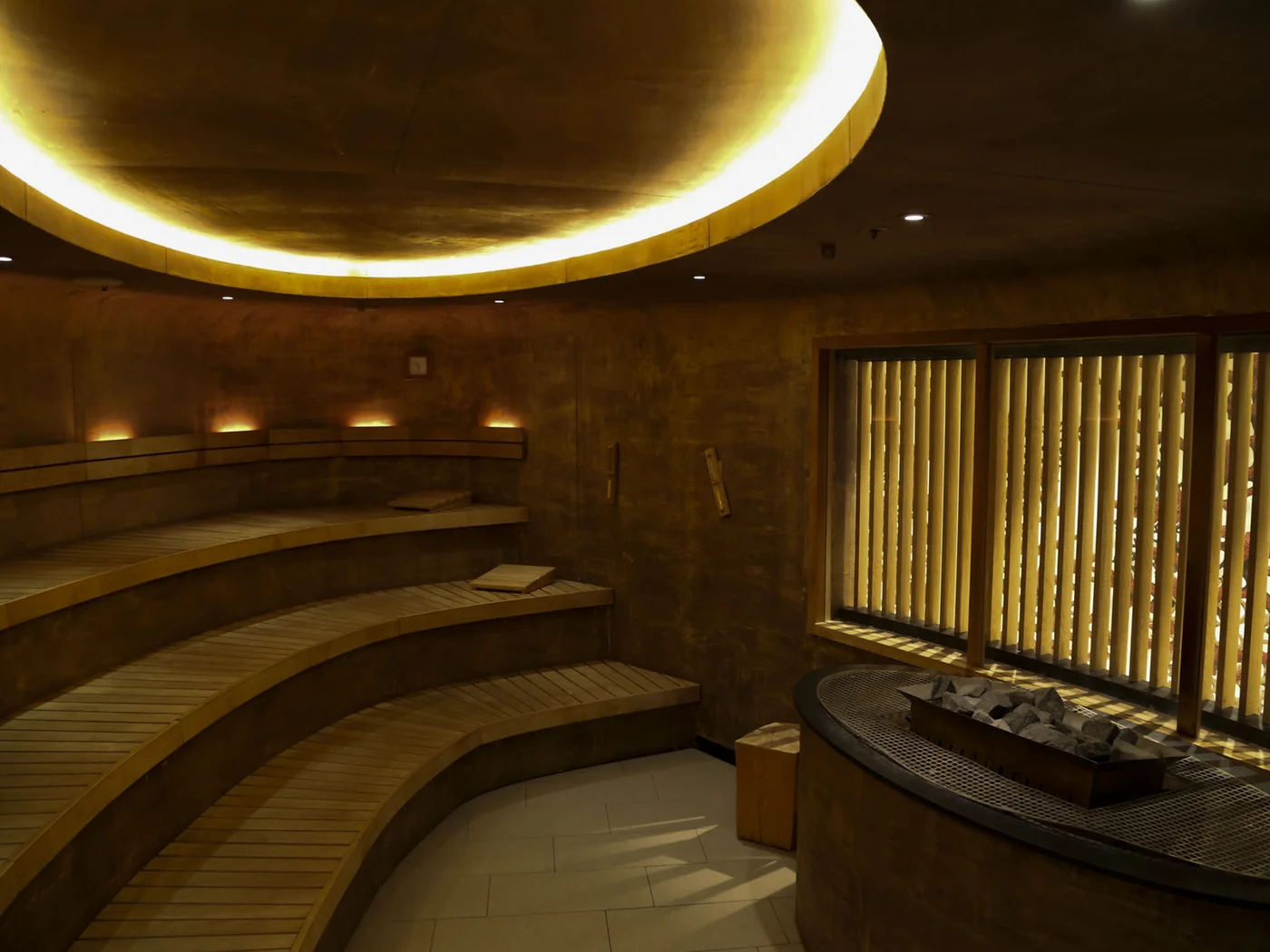 Die Schlossevents Innenraum einer modernen Sauna mit gebogenen Holzliegen und indirekter Beleuchtung