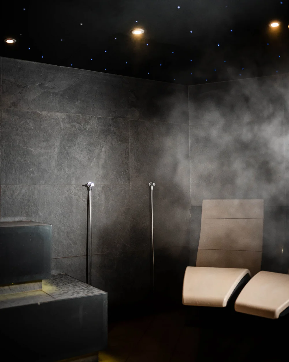 In Kitzbühel ein Hotel mit Pool, bitte. Moderne Dampfbad-Lounge mit gedämpftem Licht und bequemen Liegestühlen