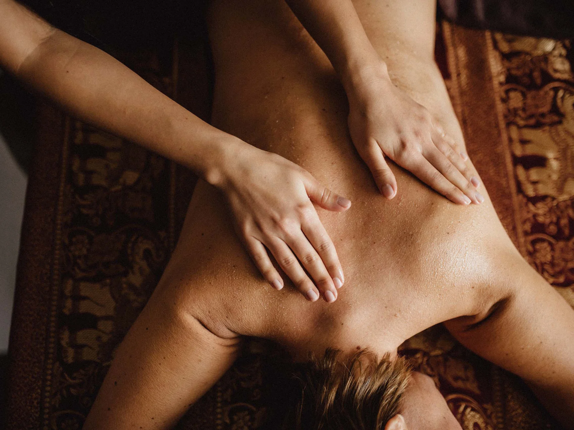 Bilder, die Sie sehen müssen. Person erhält eine Rückenmassage auf einer braunen Massagebank