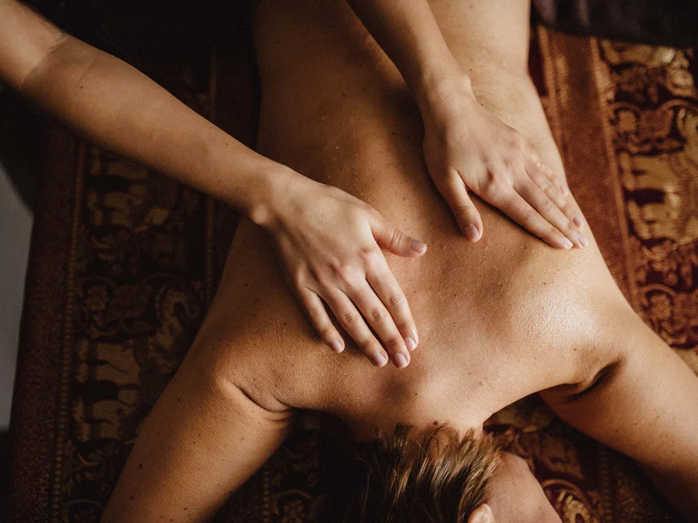 Bilder, die Sie sehen müssen. Person erhält eine Rückenmassage auf einer braunen Massagebank