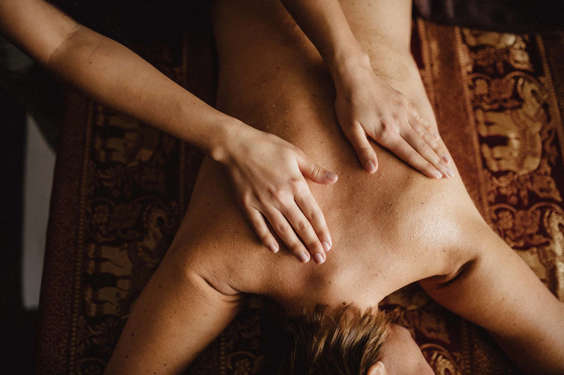 Premium-Spa im Wellnesshotel in Kitzbühel Person erhält eine Rückenmassage auf einer braunen Massagebank