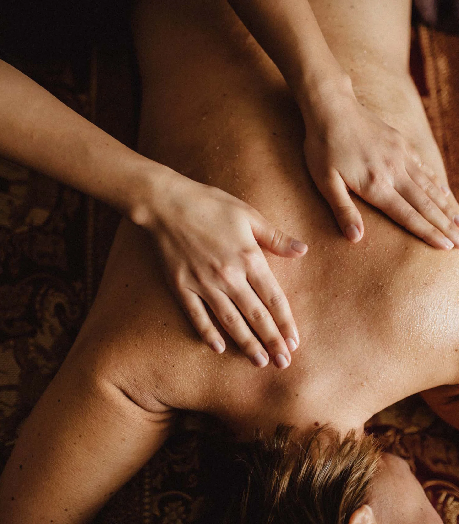 Fitness und Yoga im Hotel in Tirol Person erhält eine Rückenmassage auf einer braunen Massagebank