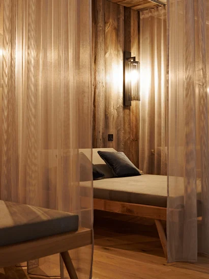 Premium-Spa im Wellnesshotel in Kitzbühel Entspannungsbereich mit Holzliegen und transparenten Vorhängen