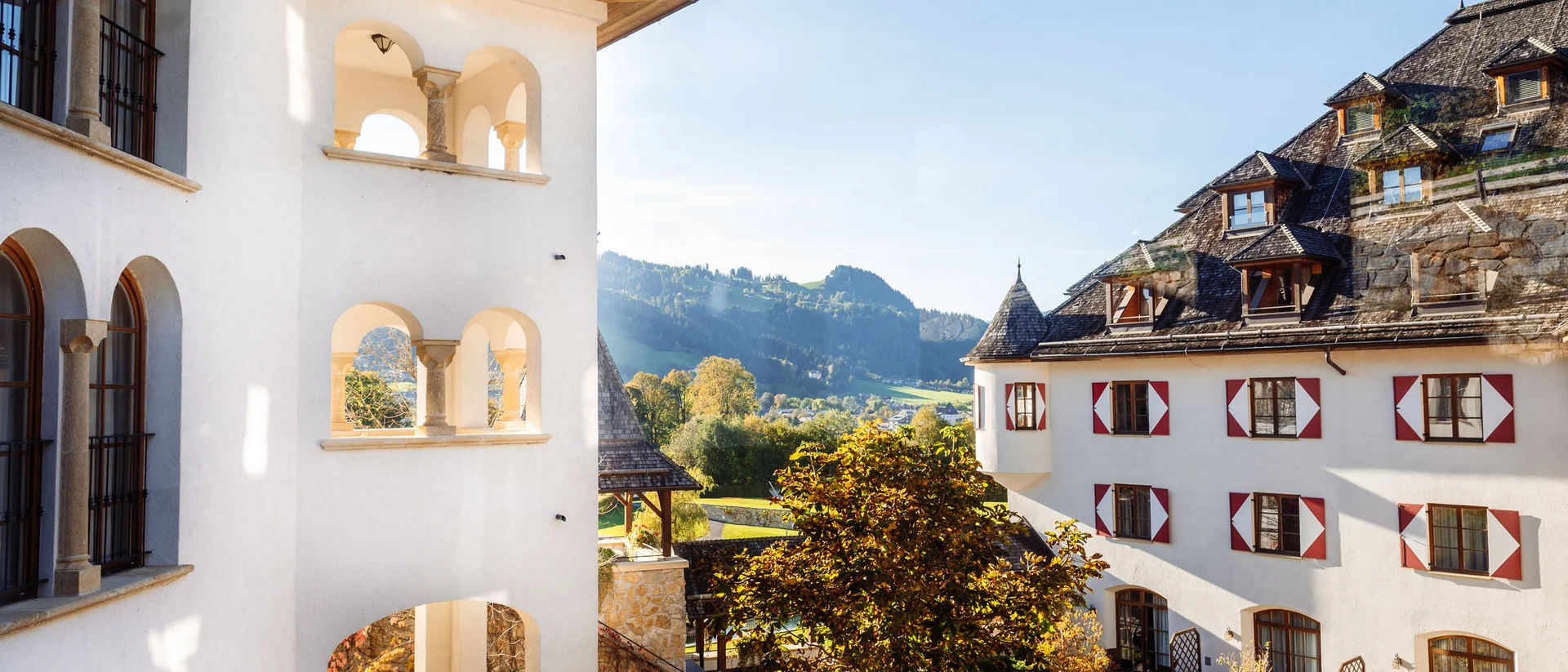 Was zählt, sind die Menschen. Blick auf historischen Gebäudekomplex mit Innenhof und Bergen im Hintergrund