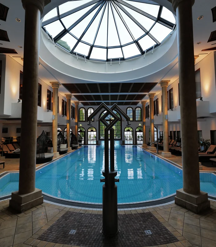 Premium-Spa im Wellnesshotel in Kitzbühel Innenaufnahme eines eleganten Hallenbads mit Glasdach und Säulen