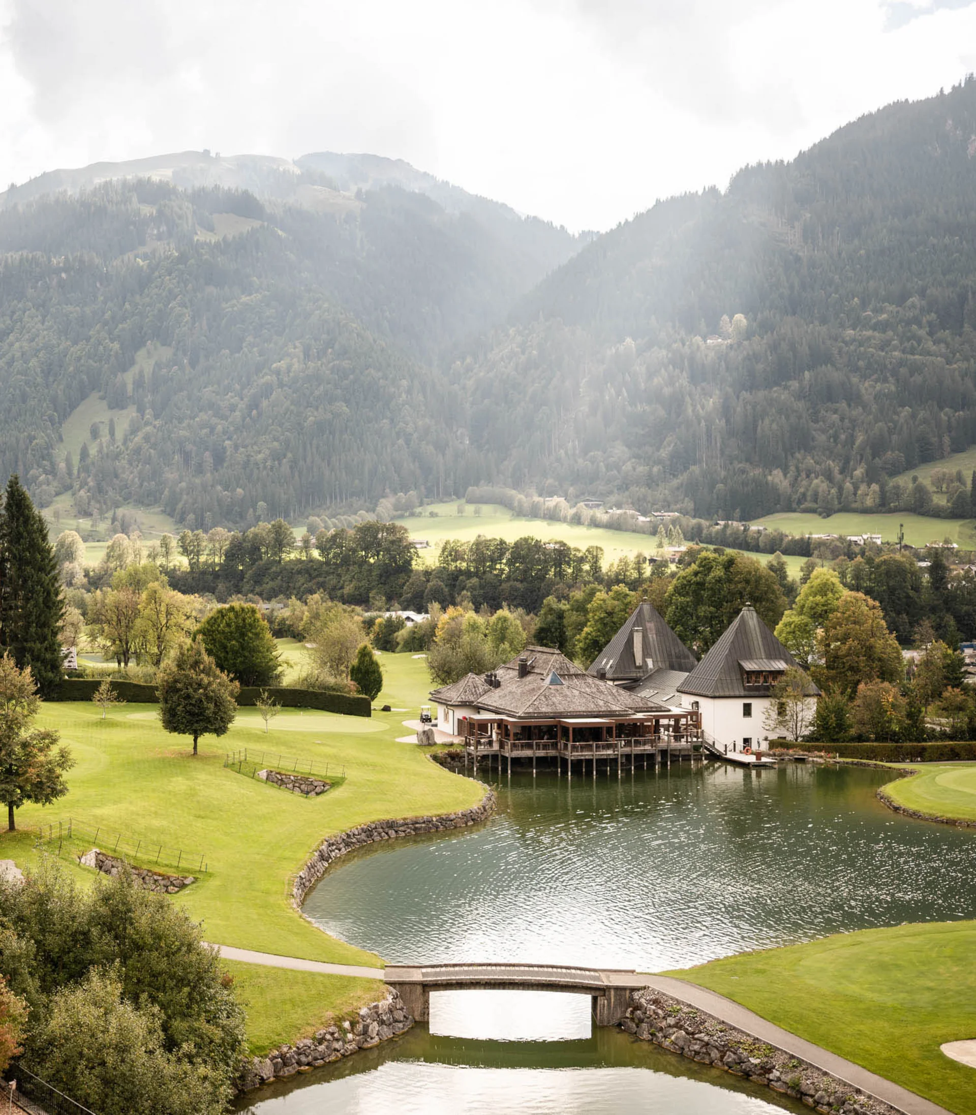 Restaurant Kitzbühel | Genuss im Schlosshotel Schlossbau mit See und grüner Landschaft vor bewaldetem Berg