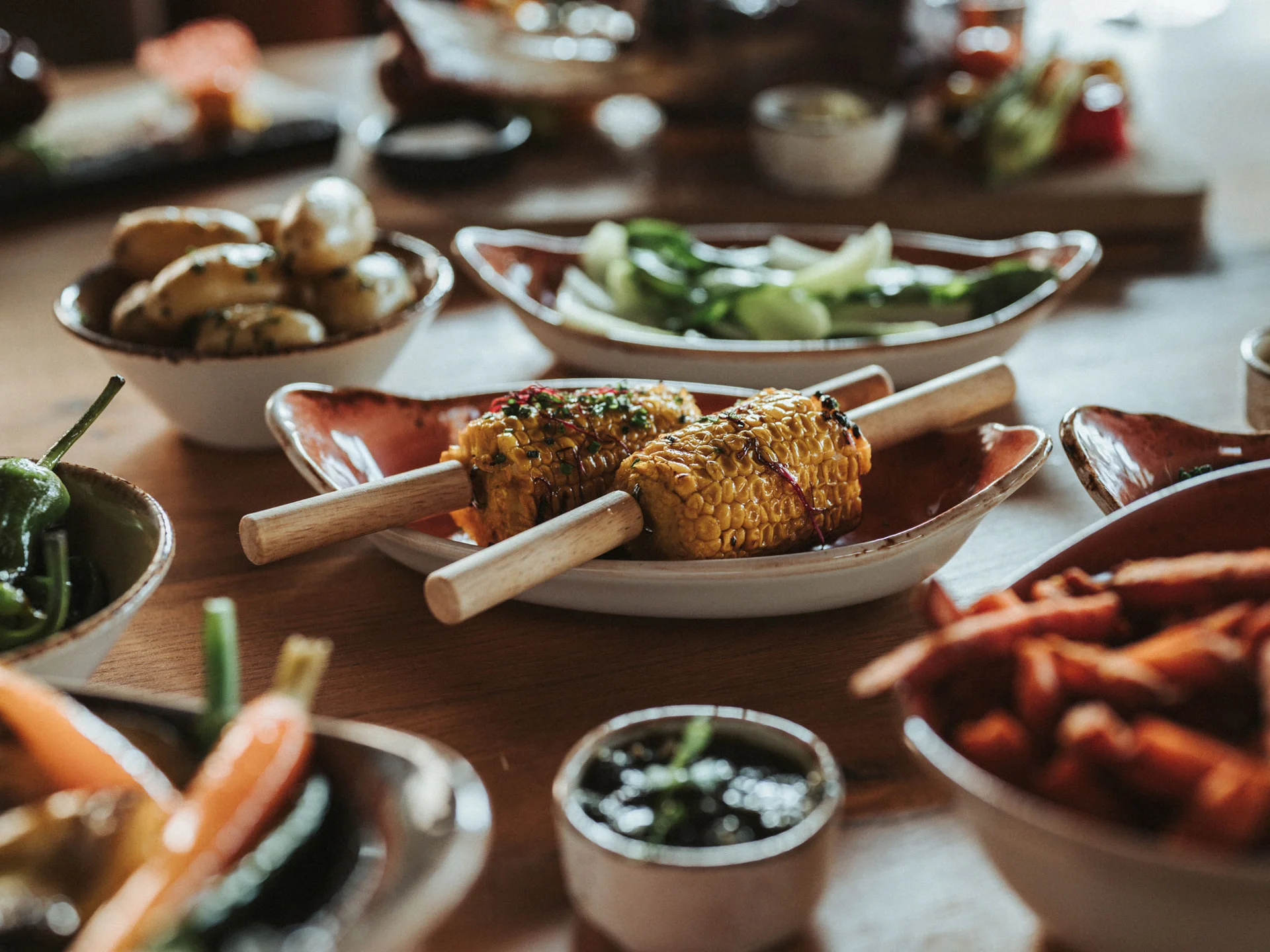 Bilder, die Sie sehen müssen. Gegrillter Mais mit verschiedenen Beilagen auf einem Holztisch