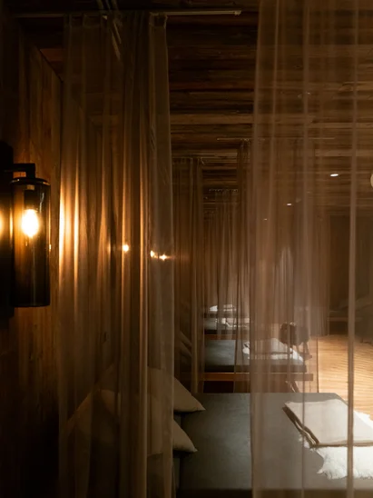 Premium-Spa im Wellnesshotel in Kitzbühel Dunkler Raum mit Betten hinter transparenten Vorhängen und warmem Wandlicht