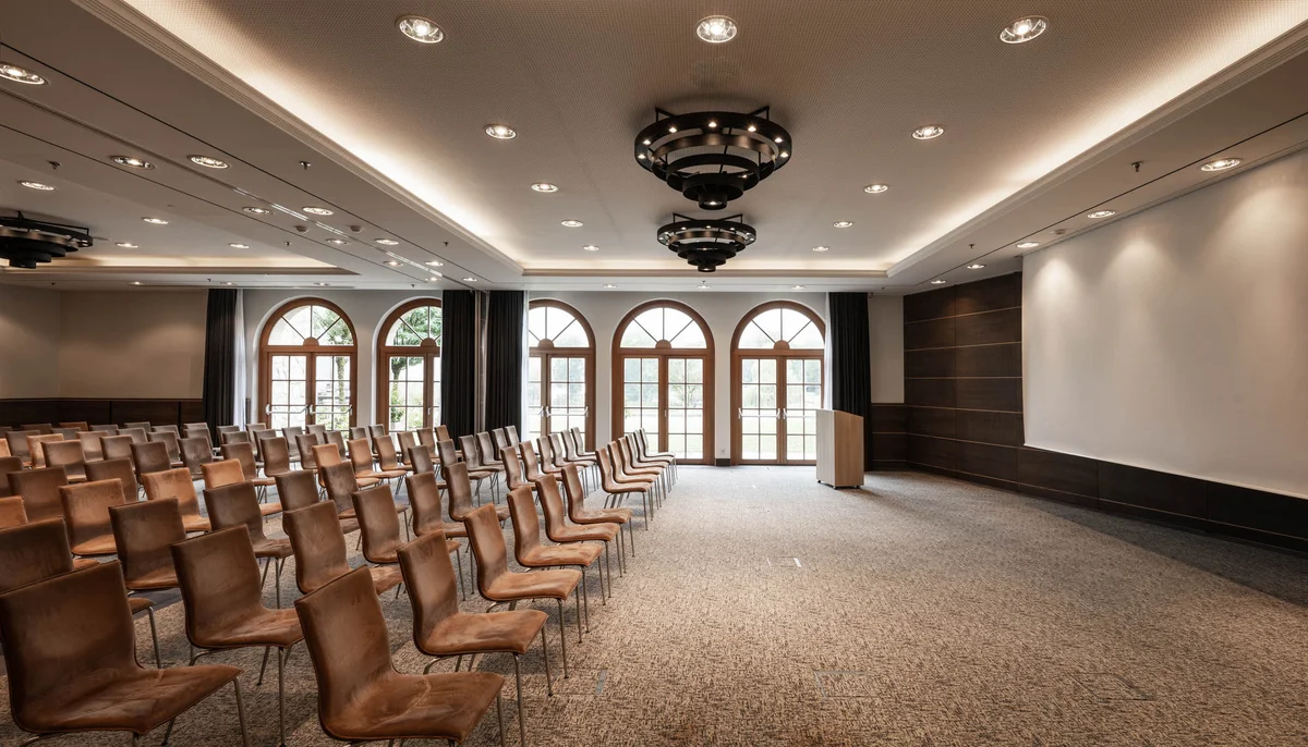 Ihr Firmenevent oder Meeting im Schlosshotel Kitzbühel Leerer Konferenzraum mit Reihen von Lederstühlen und großer Leinwand