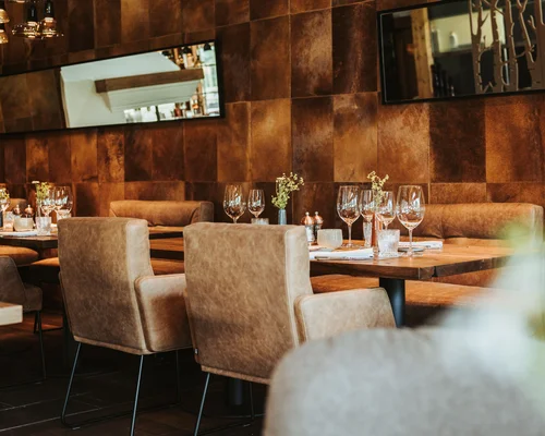 Übernachten in Kitzbühel – Zimmer und Suiten im Schlosshotel Gemütliches Restaurant mit Ledersesseln und eingedeckten Tischen