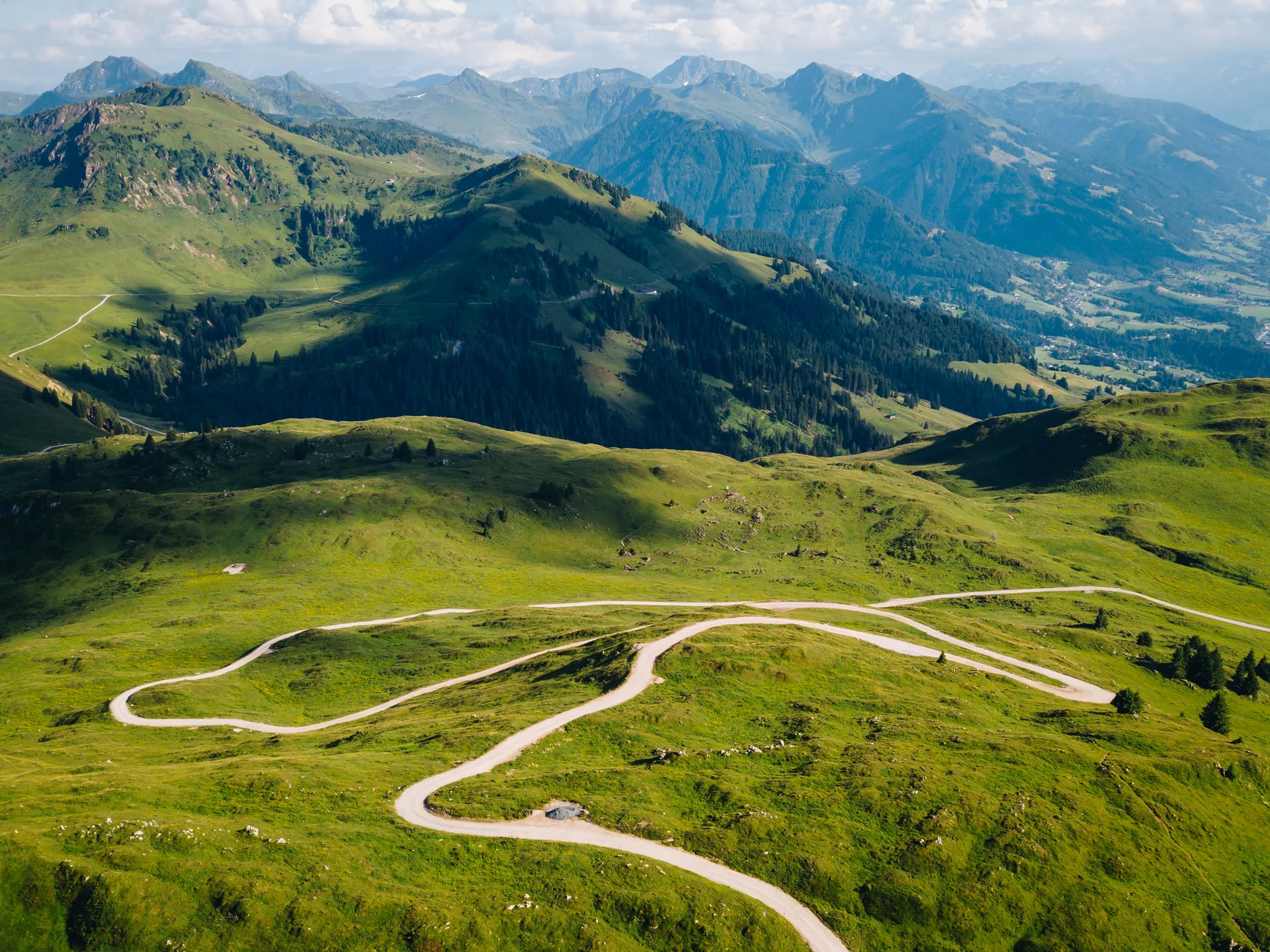 Bilder, die Sie sehen müssen. Wunderschöne grüne Berglandschaft mit gewundenen Straßen unter blauem Himmel