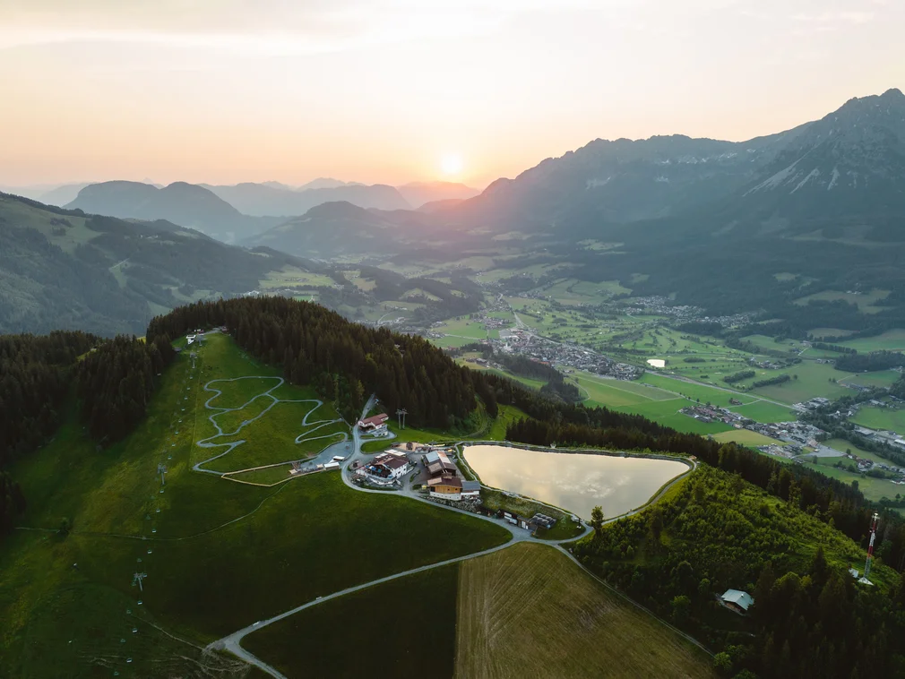 Bilder, die Sie sehen müssen. Berglandschaft bei Sonnenuntergang mit Dorf, See und Wanderwegen