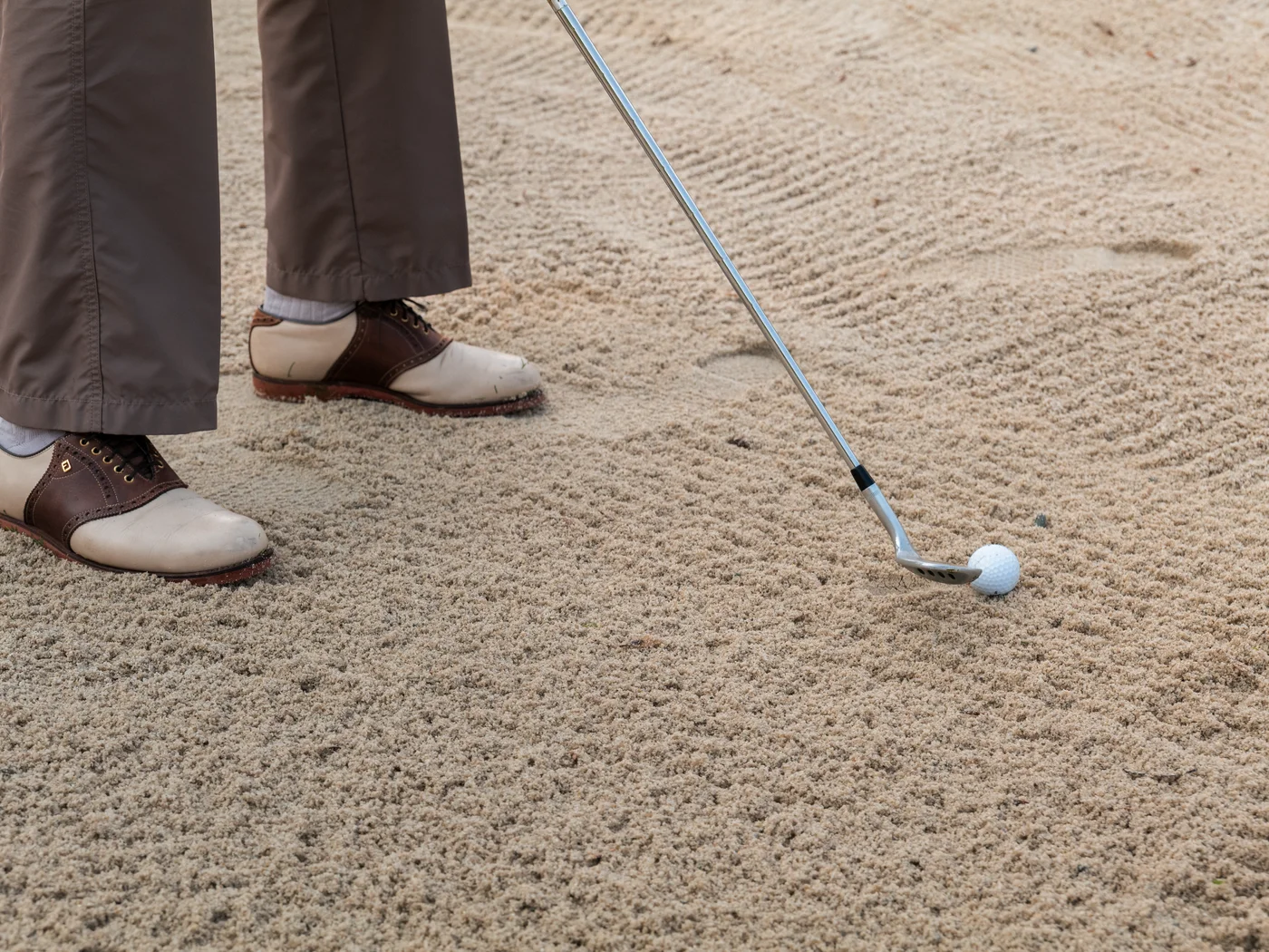 Sommer Golfschläger und Ball in einem Sandbunker mit golfer Schuhen
