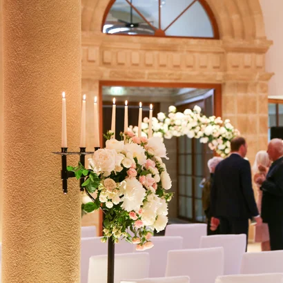 Eine der schönsten Hochzeitslocations in Tirol Blumendekoration mit Kerzen in einem festlichen Saal mit Gästen