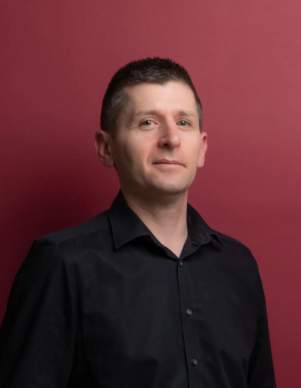 Was zählt, sind die Menschen. Porträt eines Mannes mit schwarzen Hemd vor rotem Hintergrund