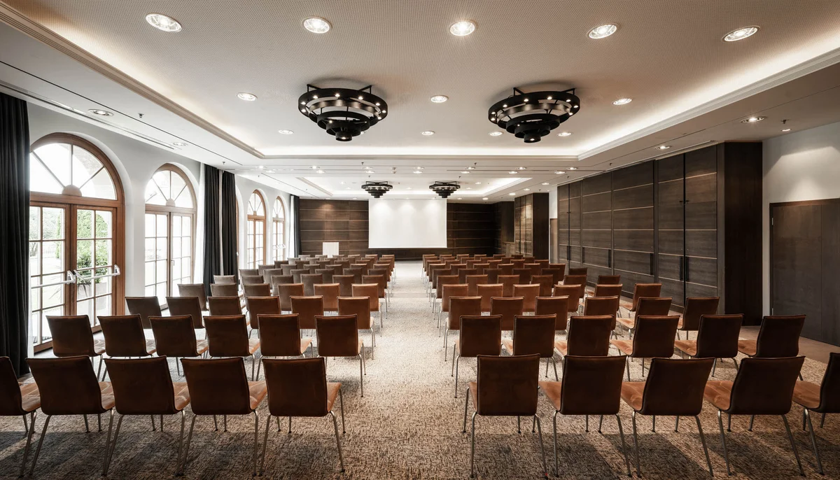Ihr Firmenevent oder Meeting im Schlosshotel Kitzbühel Leerer moderner Konferenzraum mit Reihen von Stühlen und Projektionsleinwand