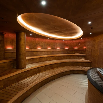 Exklusiv tagen im Seminarhotel in Tirol Moderner, runder Saunaraum mit Holzliegen und indirekter Deckenbeleuchtung