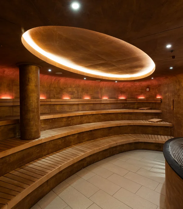 In Kitzbühel ein Hotel mit Pool, bitte. Moderner, runder Saunaraum mit Holzliegen und indirekter Deckenbeleuchtung