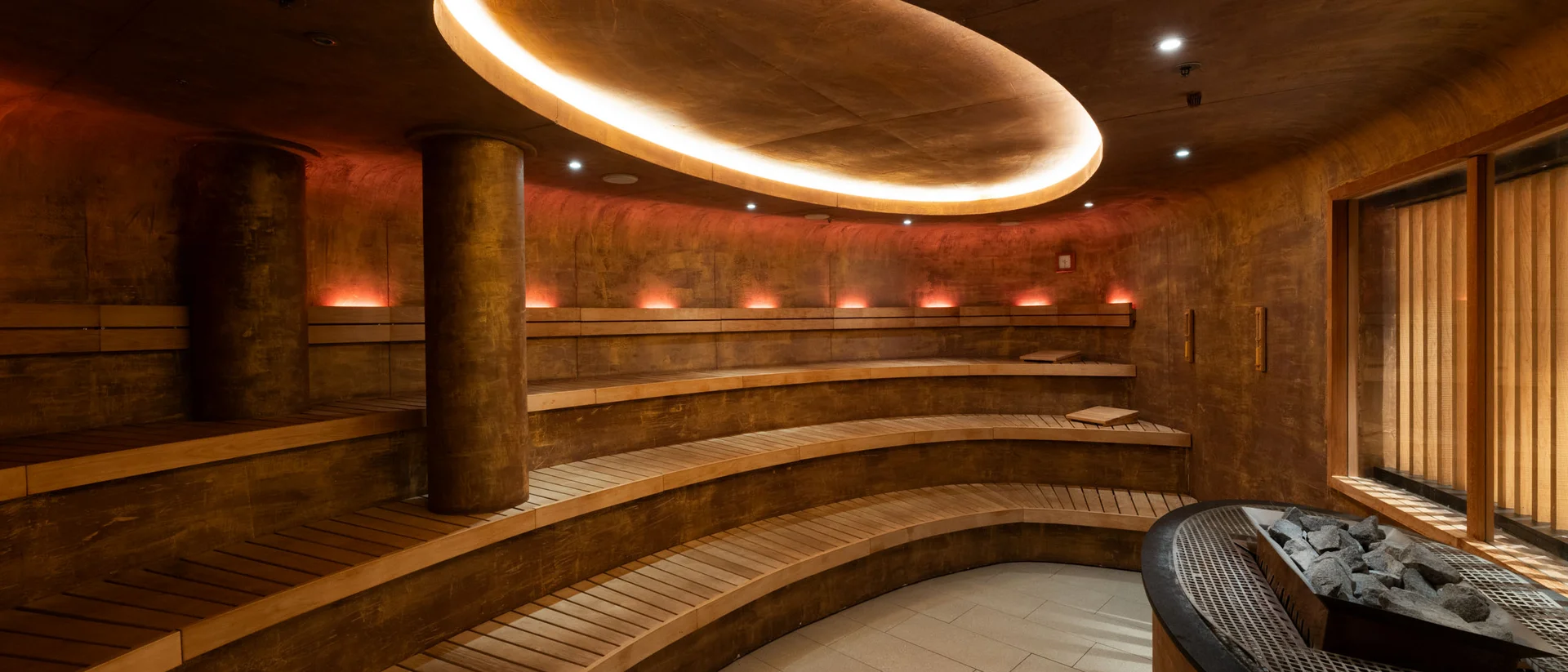 Schlosshotel Day Spa Moderner, runder Saunaraum mit Holzliegen und indirekter Deckenbeleuchtung