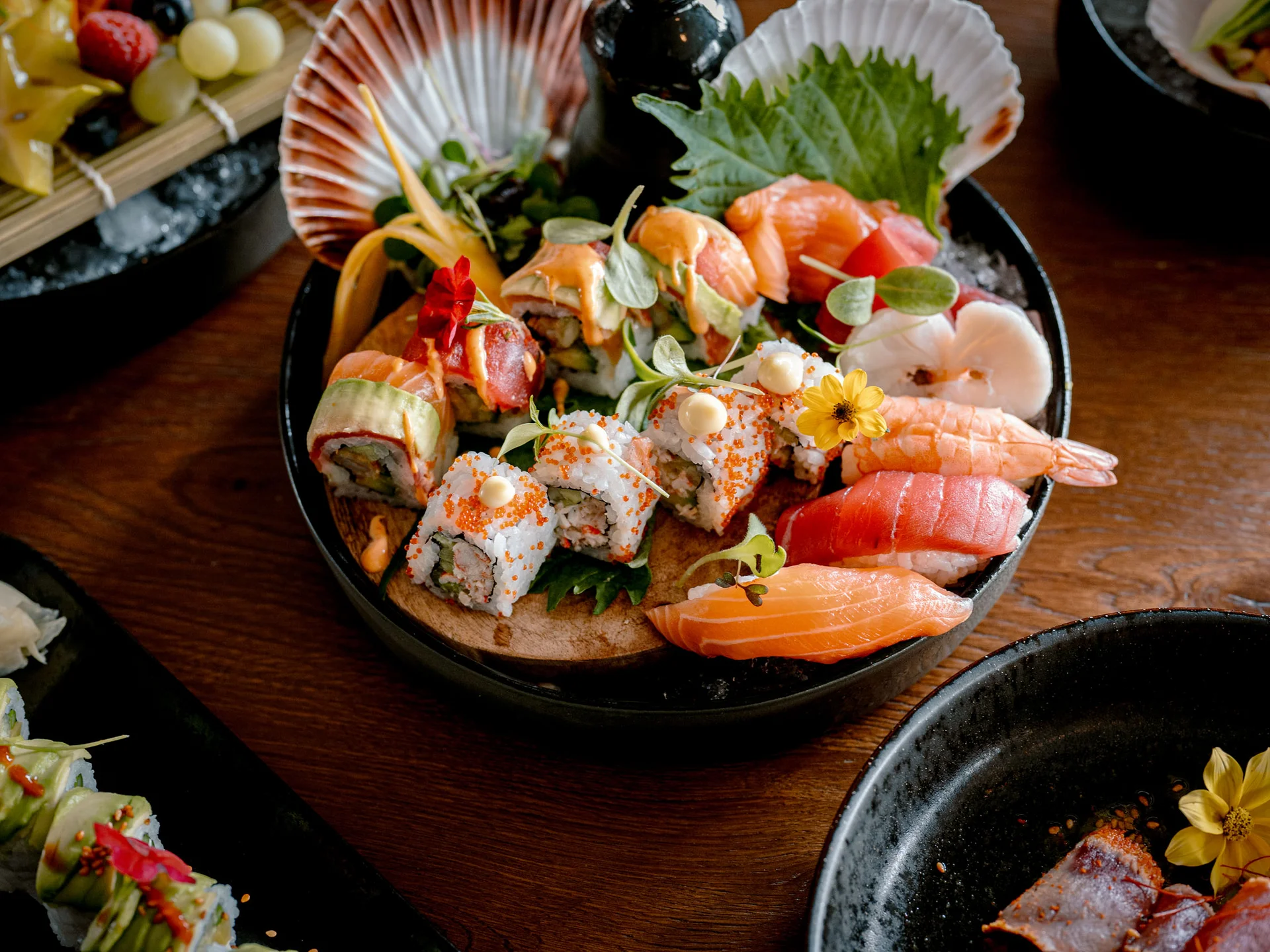 Bilder, die Sie sehen müssen. Verschiedene Sushi und Sashimi auf einem schwarzen Teller mit Dekoration