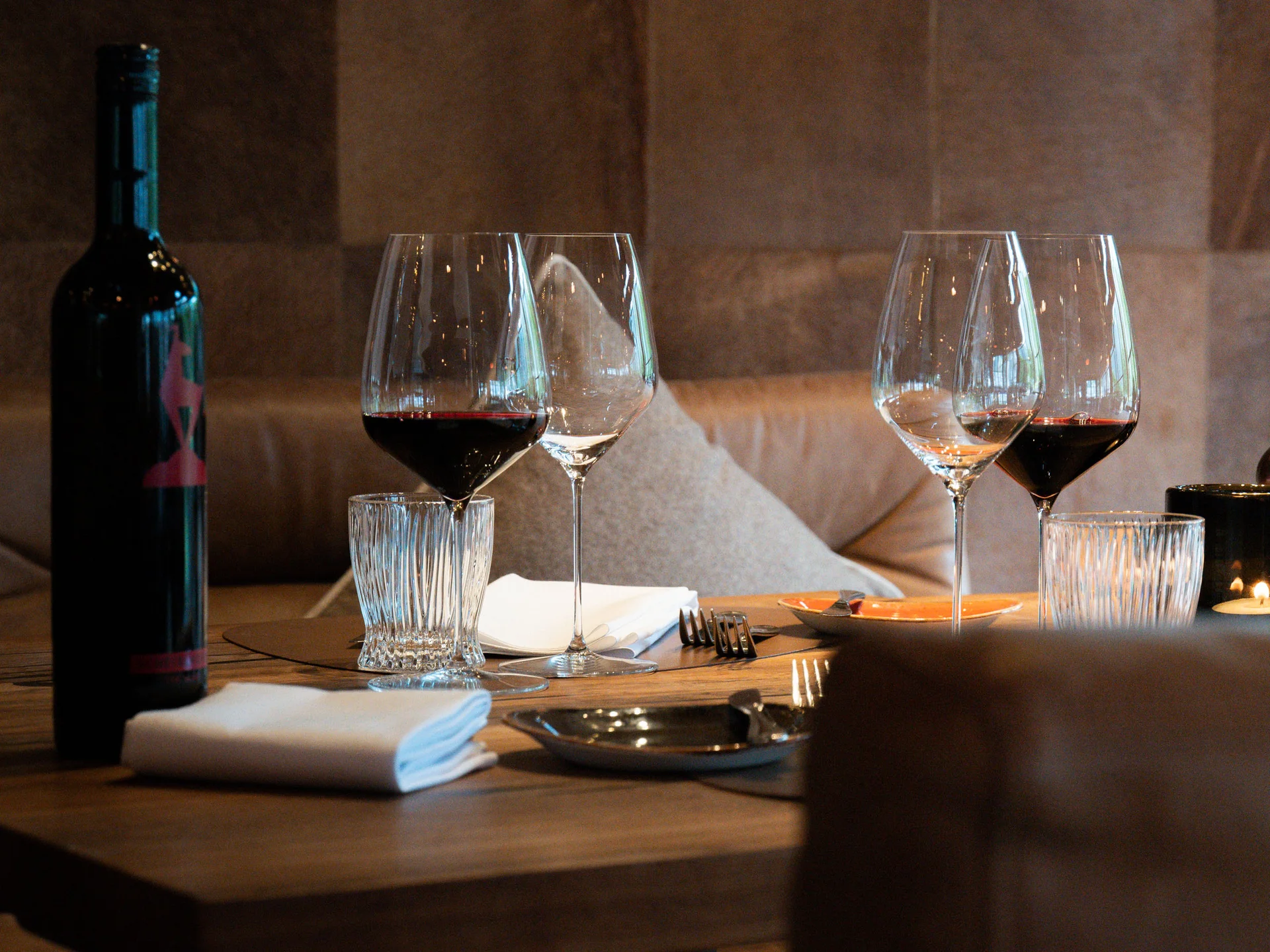 Bilder, die Sie sehen müssen. Weinflasche und Weingläser auf einem gedeckten Holztisch im Restaurant