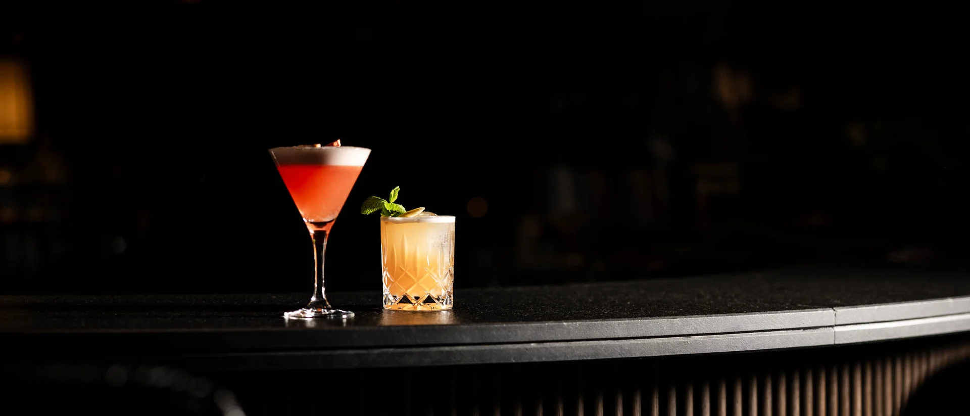 Hotel mit Klavier und Livemusik | Die Bar im Schlosshotel Kitzbühel Zwei gemischte Cocktails auf einer dunklen Bar mit Holzdetails