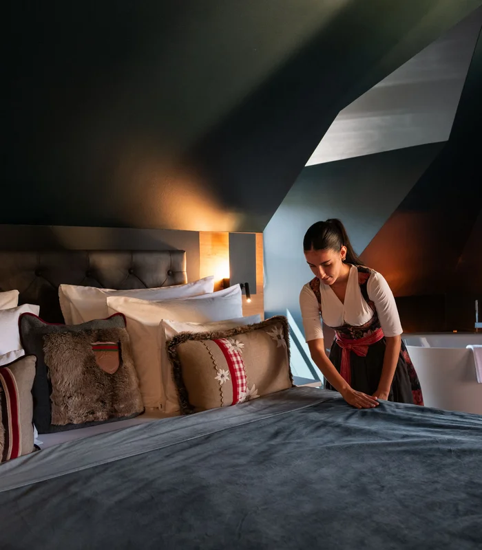 Ihre Karriere im Schlosshotel Kitzbühel Frau macht Bett in stilvollem Hotelzimmer mit Badewanne