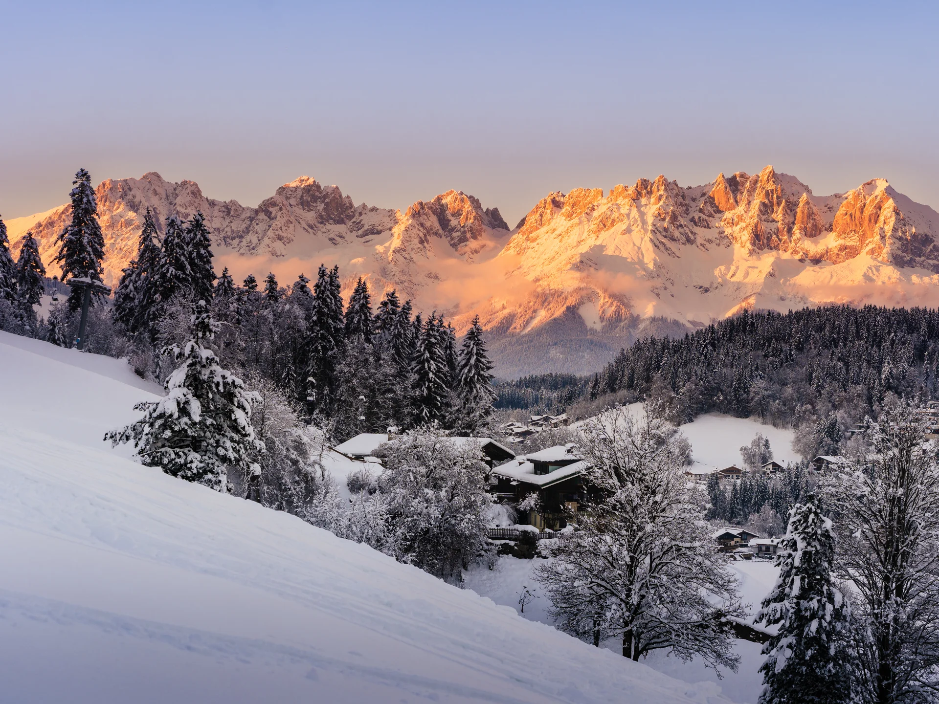 Bilder, die Sie sehen müssen. Schneebedeckte Berge und Häuser im Winter bei Sonnenuntergang
