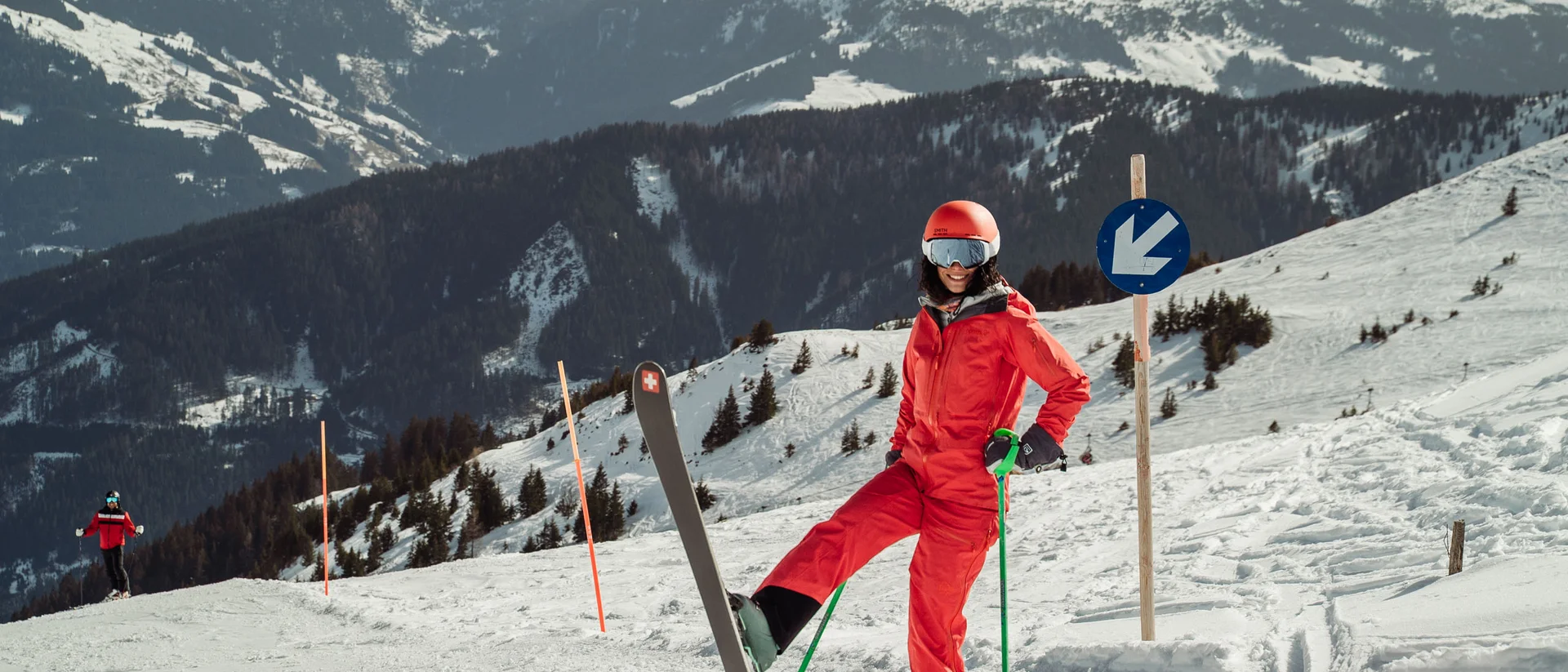 Aktiv in der Gamsstadt im Sporthotel in Kitzbühel Skifahrerin in roter Kleidung auf schneebedecktem Berg mit Bergen im Hintergrund