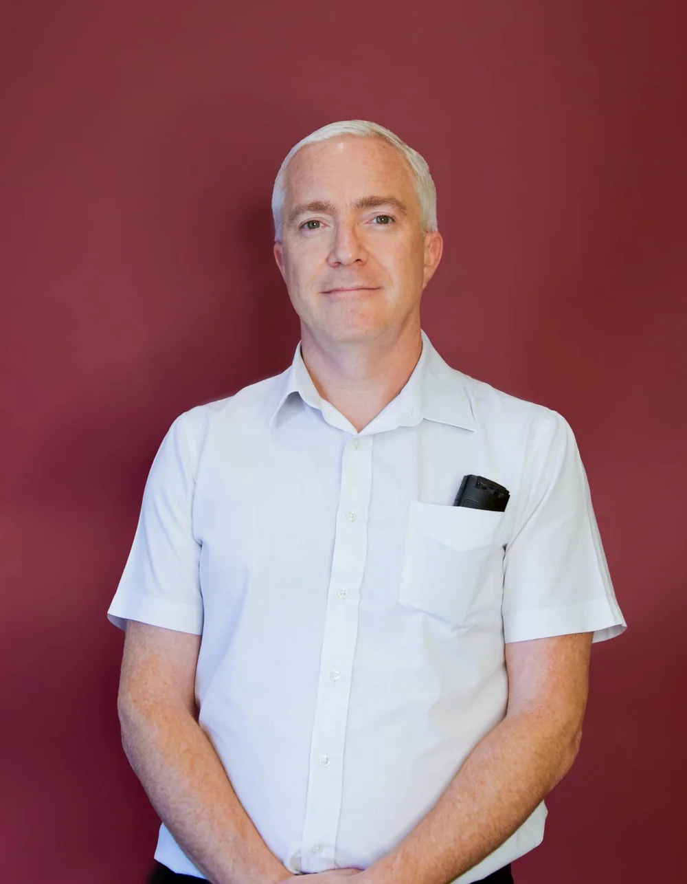 Was zählt, sind die Menschen. Mann mit weißem Hemd vor rotem Hintergrund