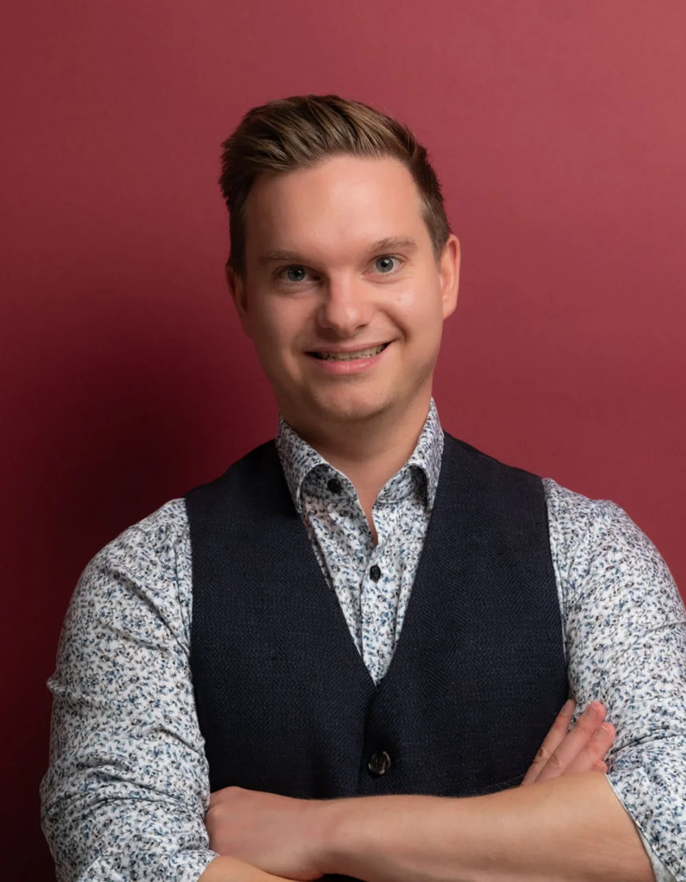 Was zählt, sind die Menschen. Junger Mann mit verschränkten Armen vor rotem Hintergrund