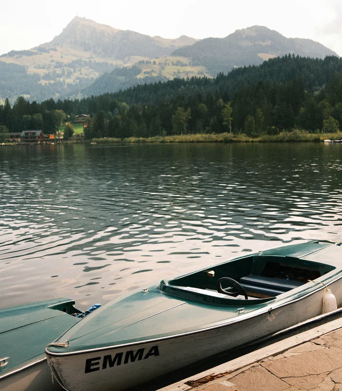 Wonach steht Ihnen heute der Sinn in Kitzbühel? Motorboot namens Emma am ruhigen See vor bewaldeten Hügeln