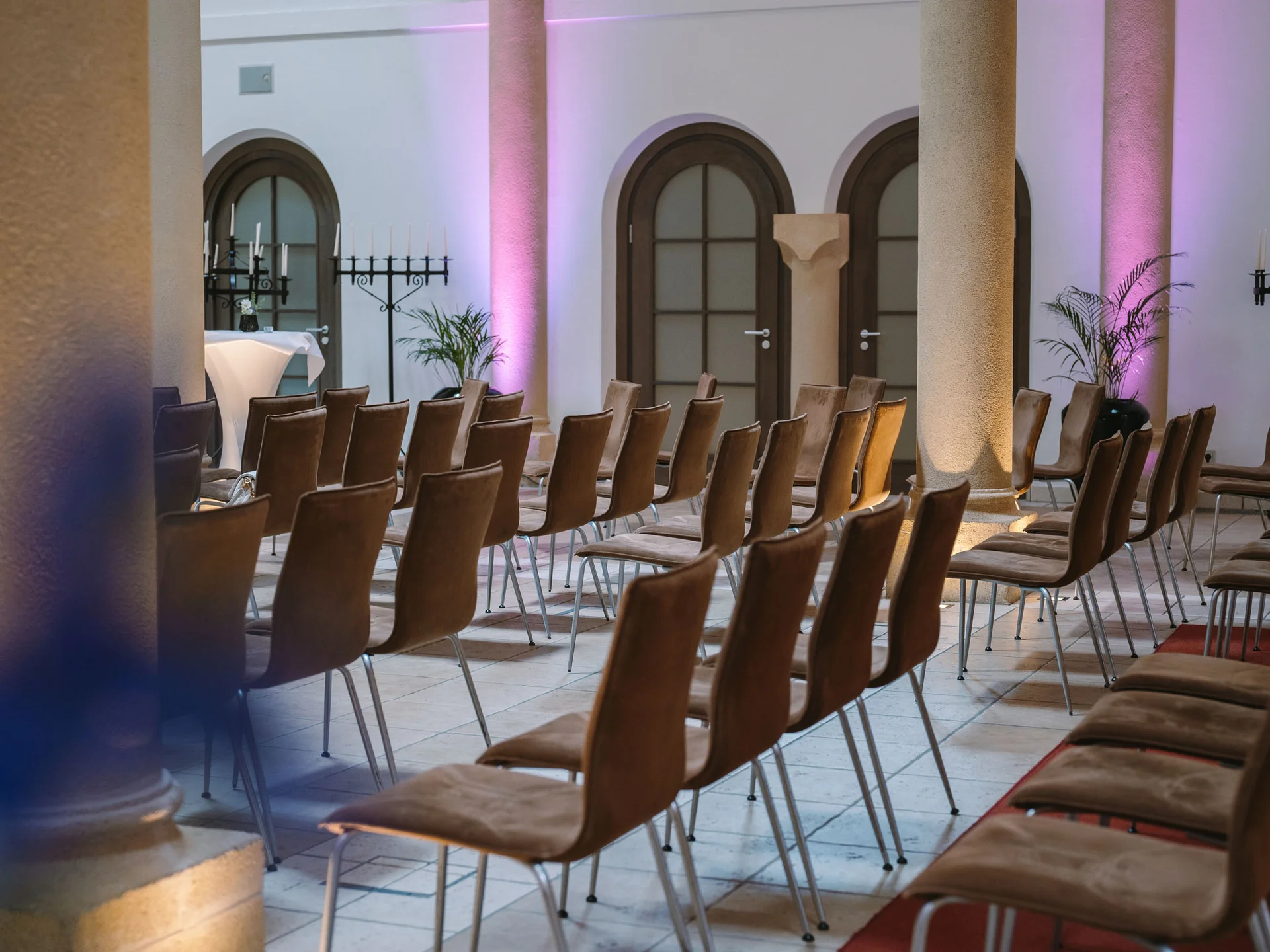 Bilder, die Sie sehen müssen. Leere Stuhlreihen in einem Raum mit Säulen und lila Beleuchtung
