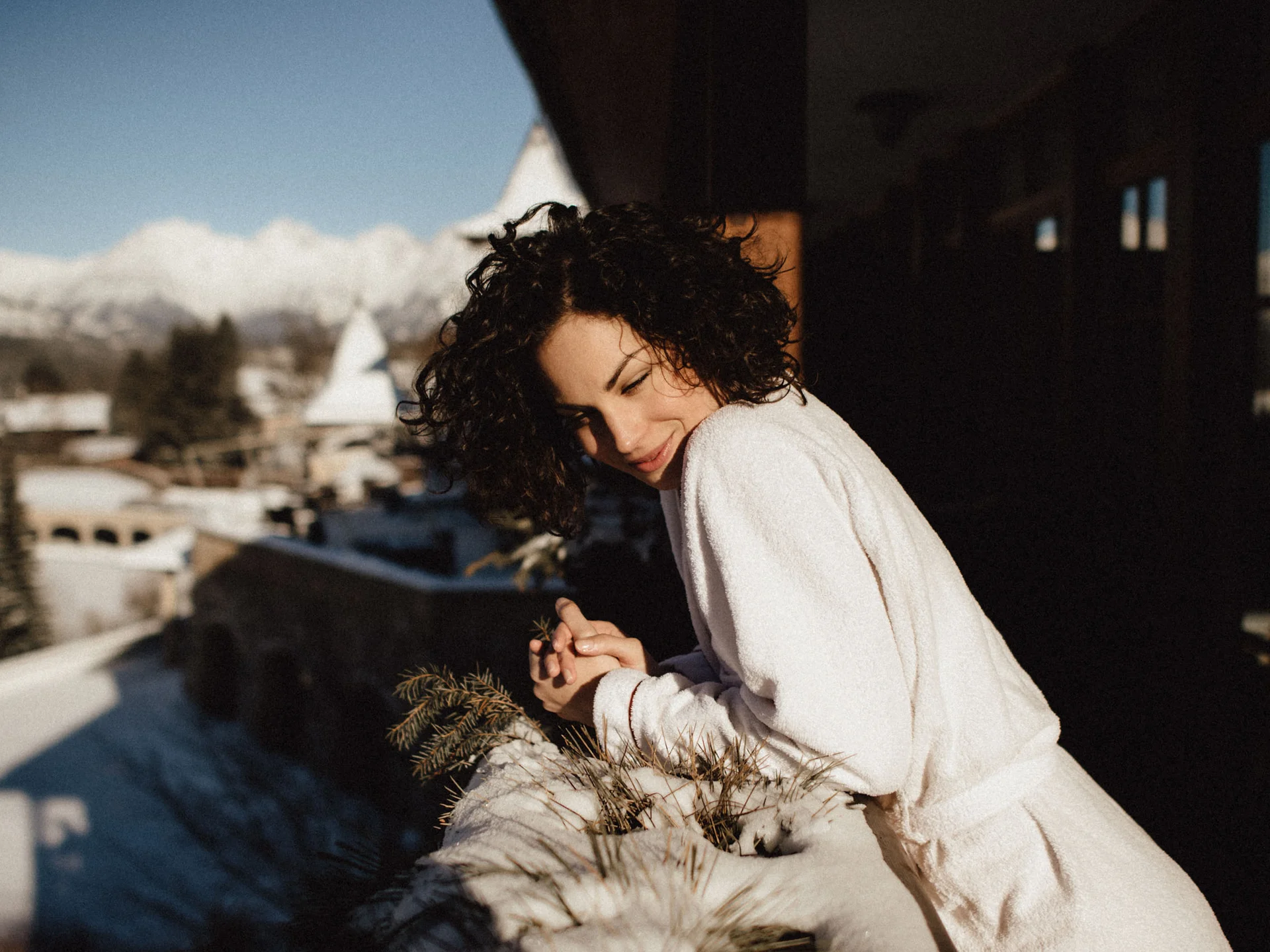 Bilder, die Sie sehen müssen. Frau in Bademantel genießt Wintersonne auf Balkon mit Bergblick