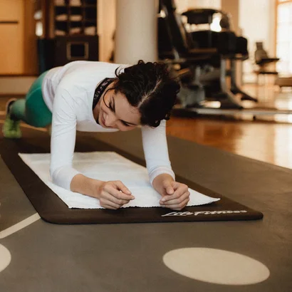 Schlosshotel Kitzbühel – un’esperienza deluxe Istruttore che incoraggia donna durante esercizio plank in palestra