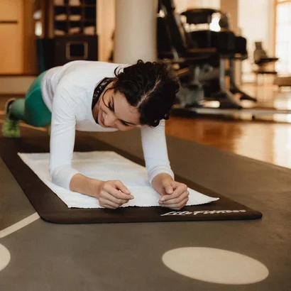 Schlosshotel Kitzbühel – a premium experience Trainer encouraging woman doing plank exercise in gym