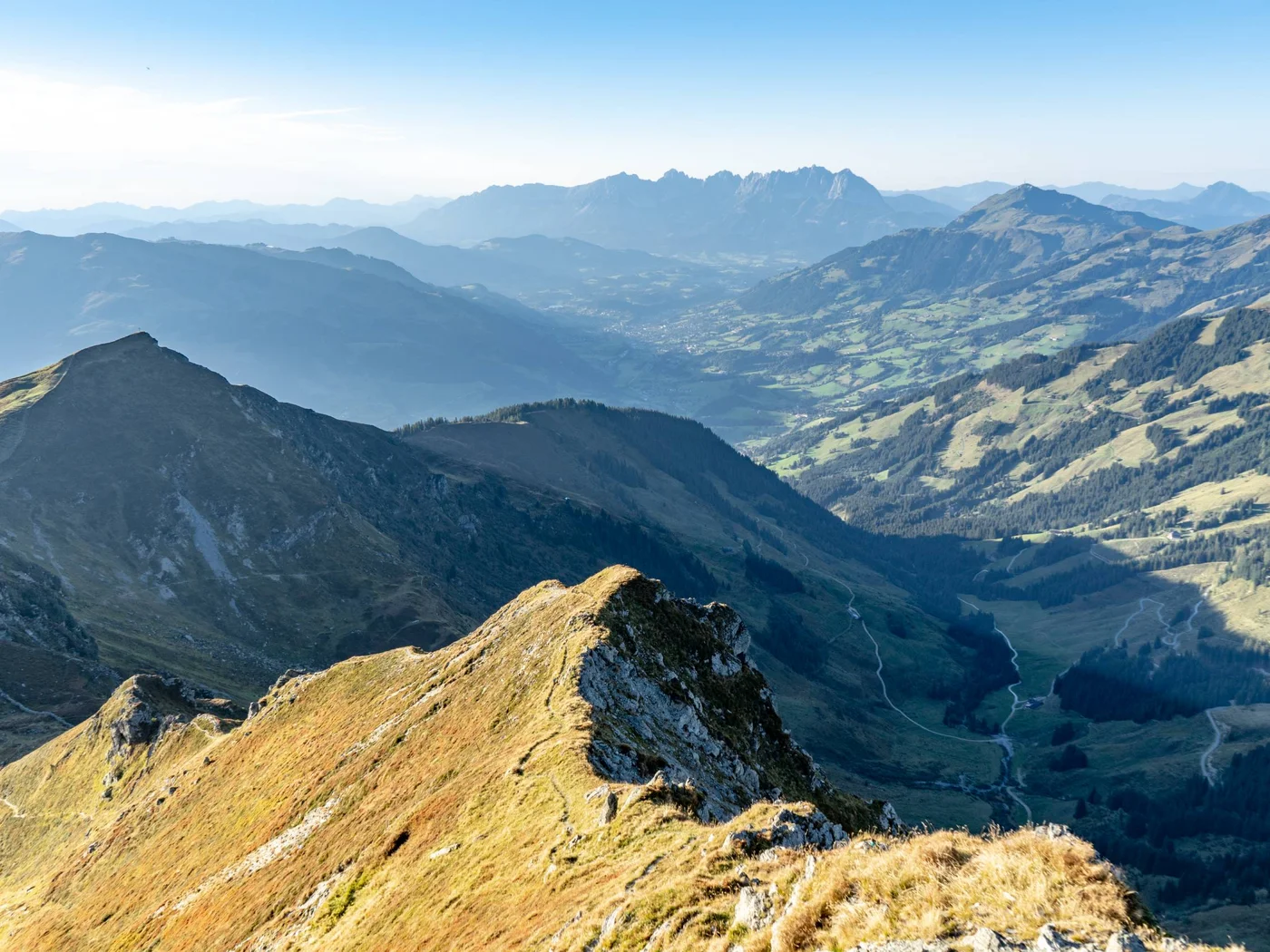 Die Schlossevents Blick auf sonnige Berggipfel und ein Tal in den Alpen bei klarem Himmel.